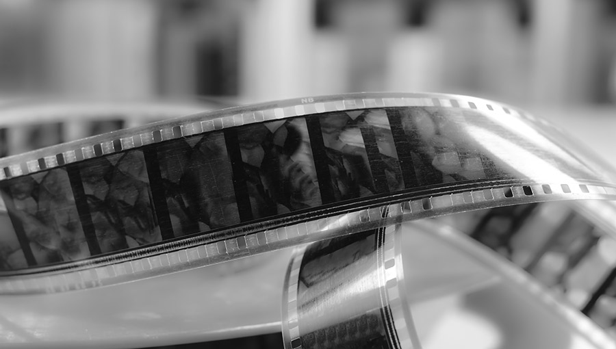 Old cine-film. Film strip on a blur background. Black and white photo.