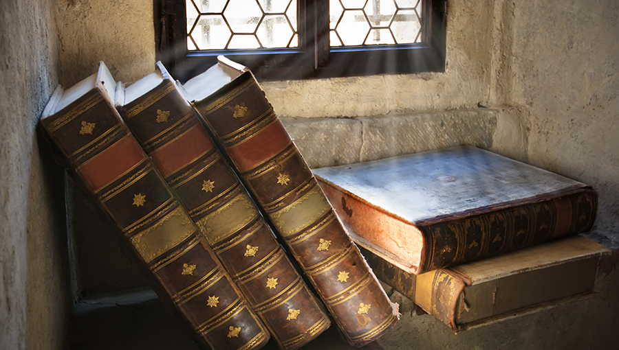 Pile of ancient books in front of window