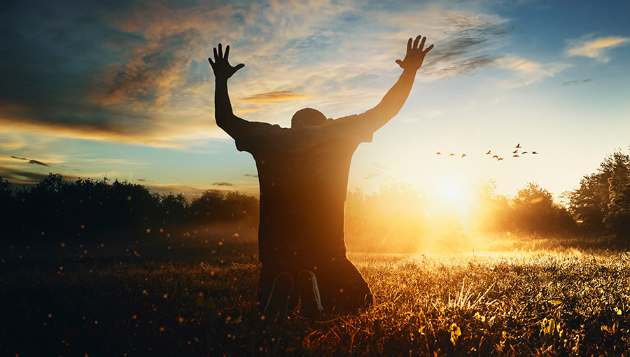 Grateful man man raising his hands in worship in the countryside.