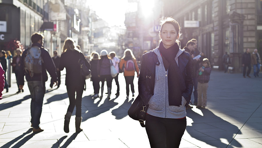 Urban girl standing out from the crowd at a city street.